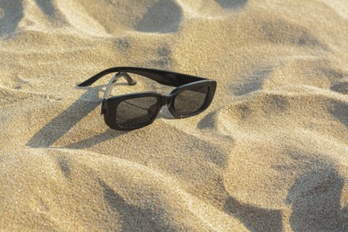 Stylish sunglasses on sandy beach, space for text