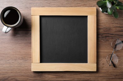 Photo of Clean small blackboard, coffee, chalk and glasses on wooden table, flat lay