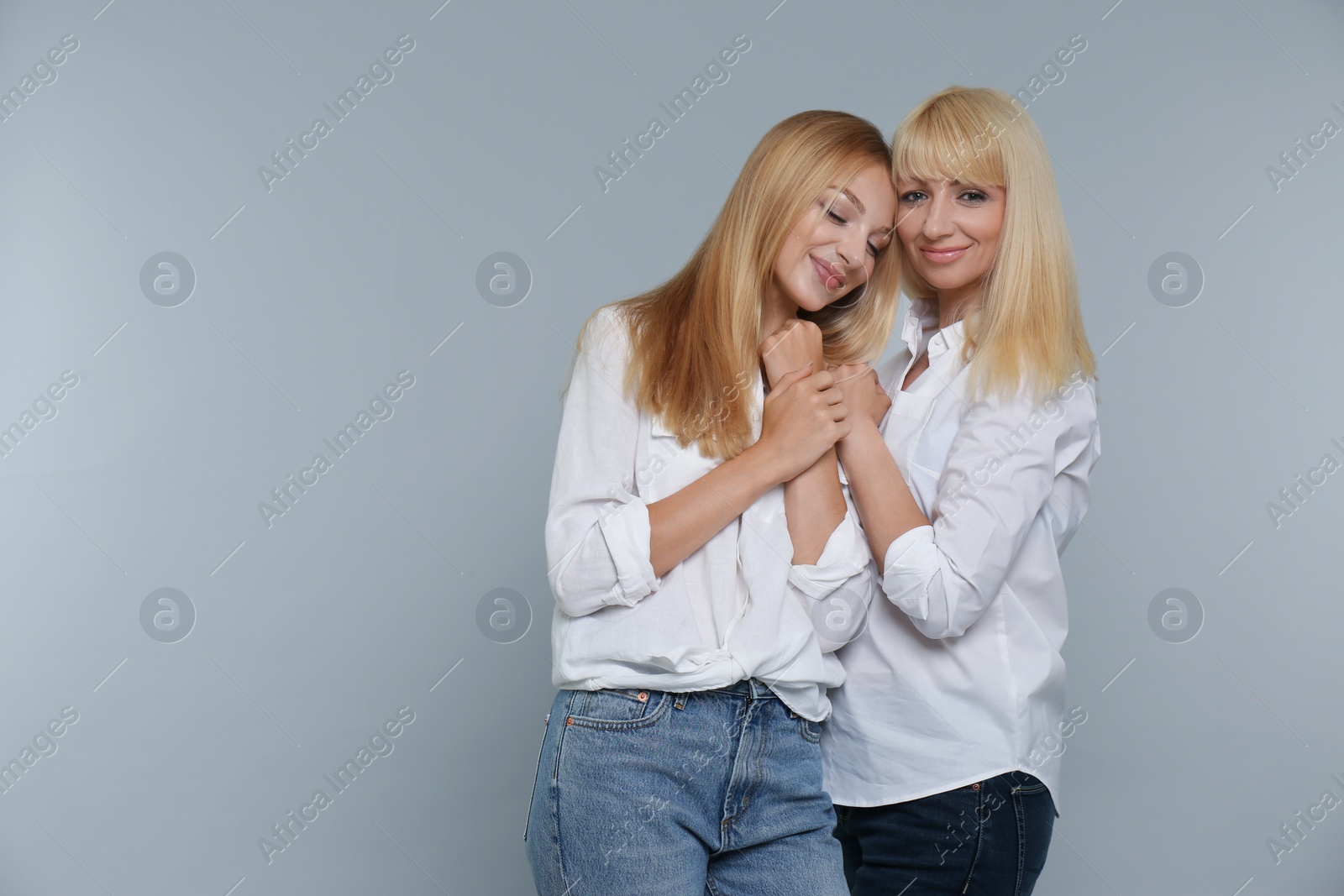 Photo of Portrait of young woman with her mature mother on grey background, space for text