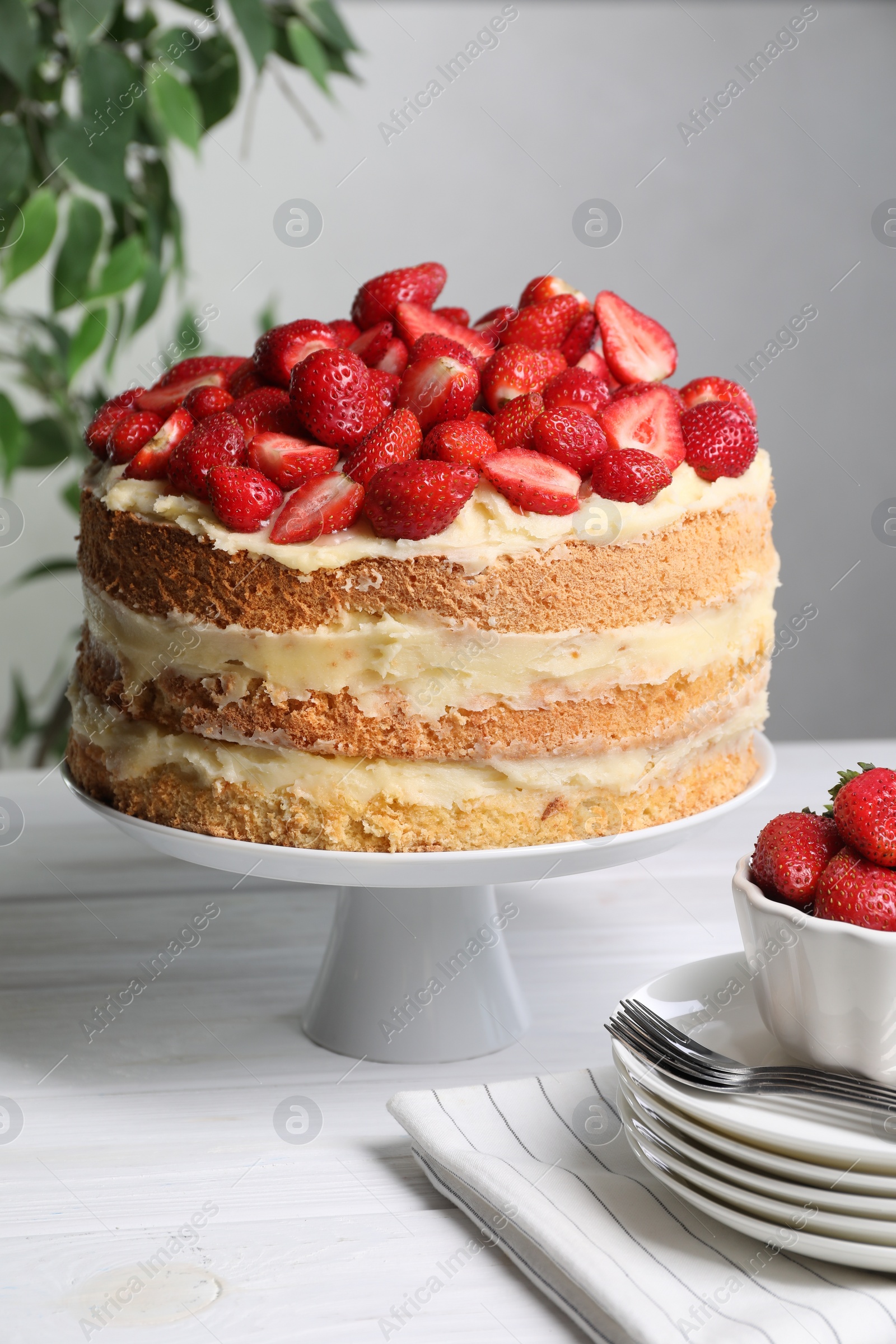 Photo of Tasty cake with fresh strawberries served on white wooden table