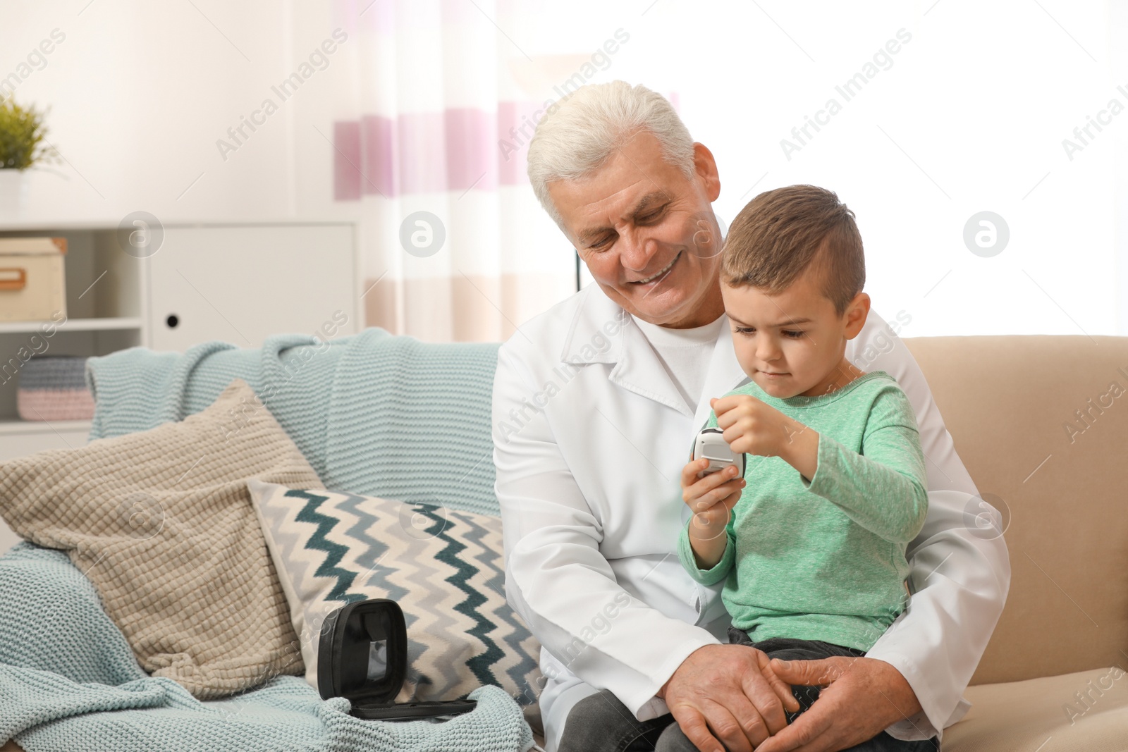 Photo of Doctor and little patient with digital glucose meter at home. Diabetes control