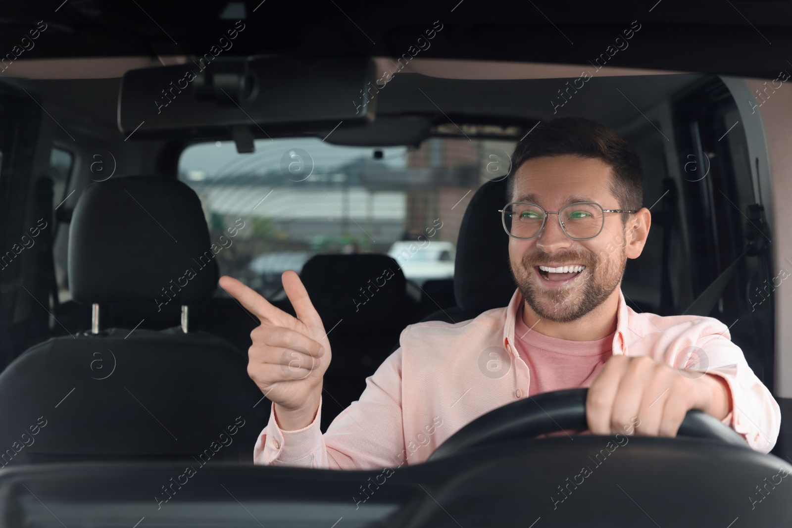 Photo of Listening to radio. Handsome man enjoying music in car, view through windshield