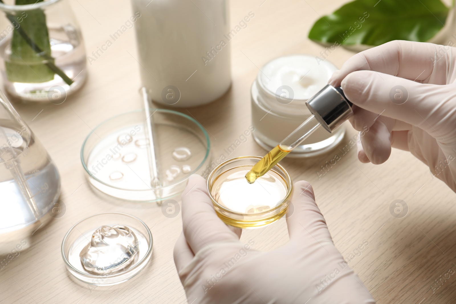 Photo of Scientist making cosmetic product at wooden table, closeup