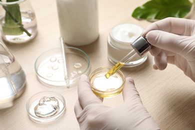 Photo of Scientist making cosmetic product at wooden table, closeup