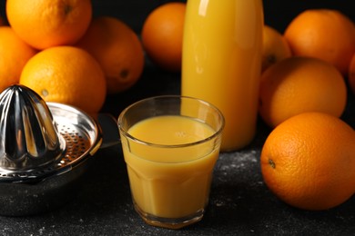 Photo of Tasty fresh oranges and juice on black table, closeup