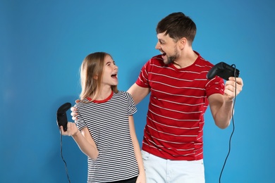 Photo of Emotional man and teenage girl playing video games with controllers on color background