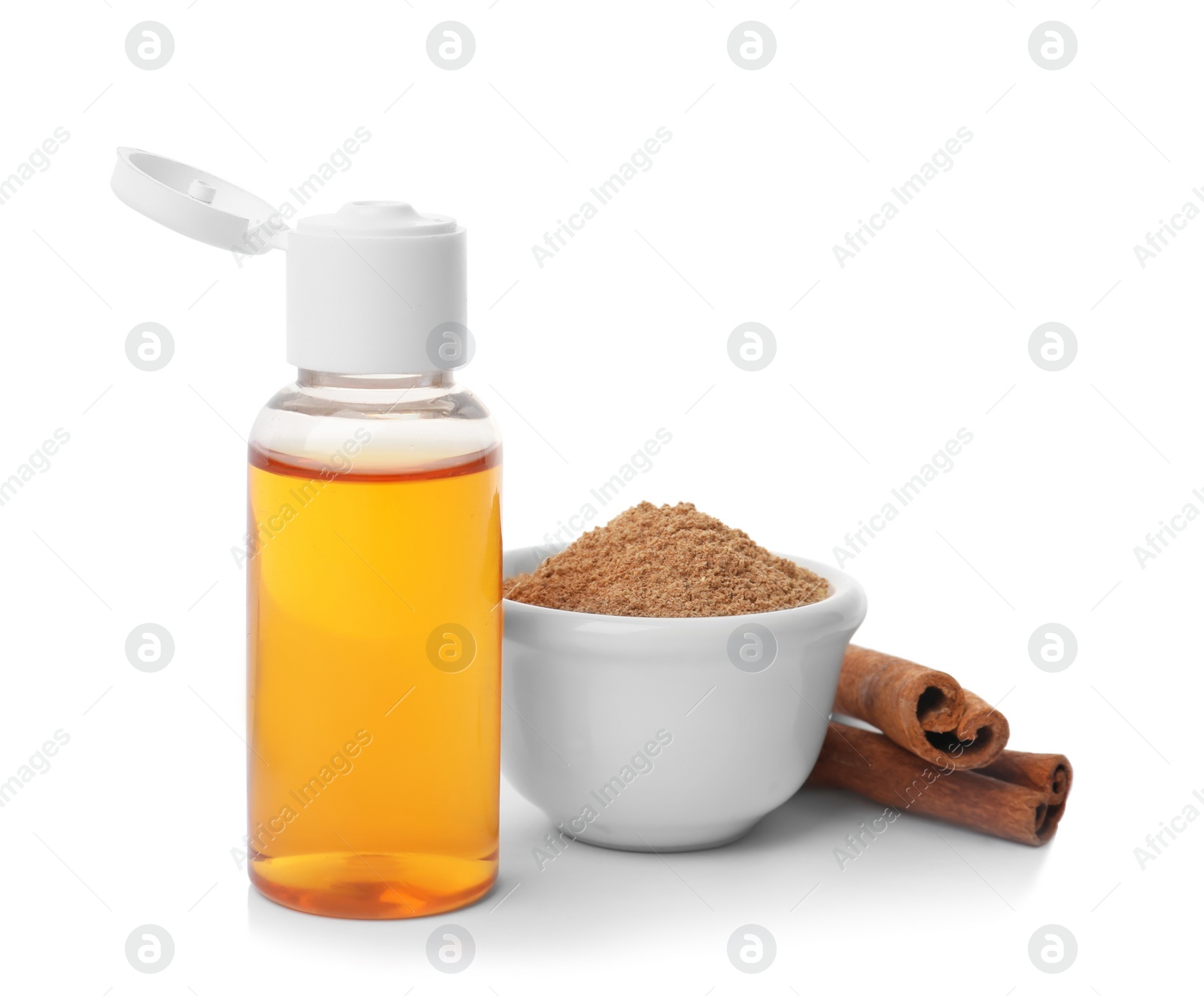 Photo of Bottle of cinnamon oil, bowl with powder and sticks on white background