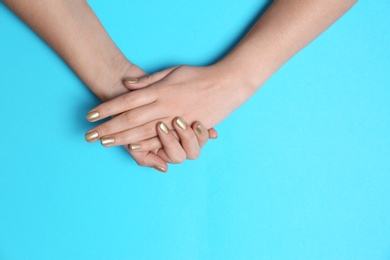 Photo of Woman showing golden manicure on color background, top view with space for text. Nail polish trends