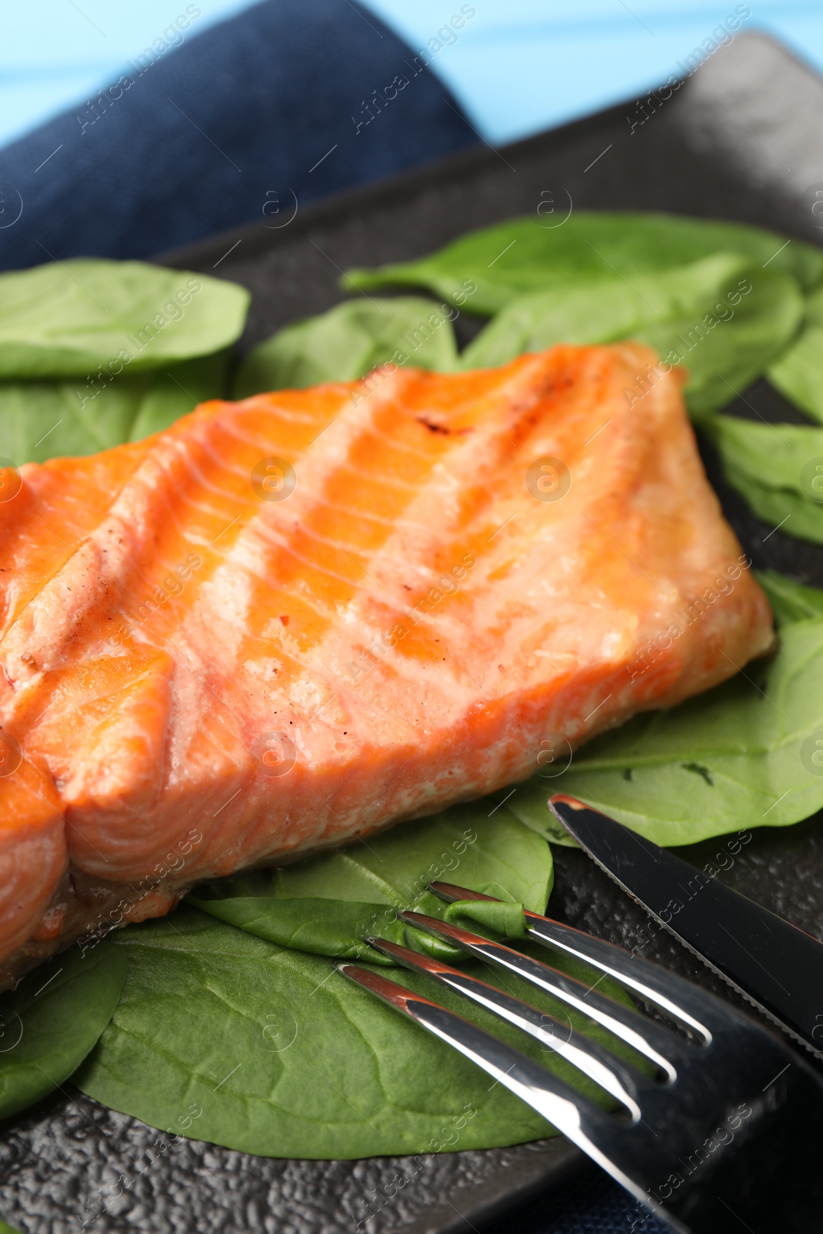 Photo of Tasty grilled salmon with spinach served on table, closeup