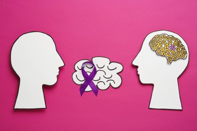 Photo of Human head cutouts, different brains and purple ribbon on crimson background, flat lay. Epilepsy awareness