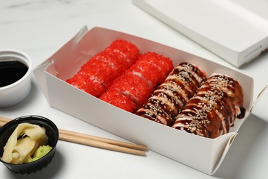 Photo of Food delivery. Delicious sushi rolls served on white table