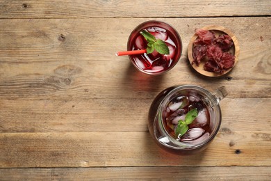 Photo of Delicious iced hibiscus tea and dry flowers on wooden table, flat lay. Space for text