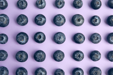 Fresh ripe blueberries on lilac background, flat lay