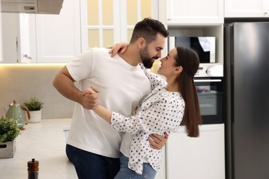 Photo of Happy lovely couple dancing together in kitchen