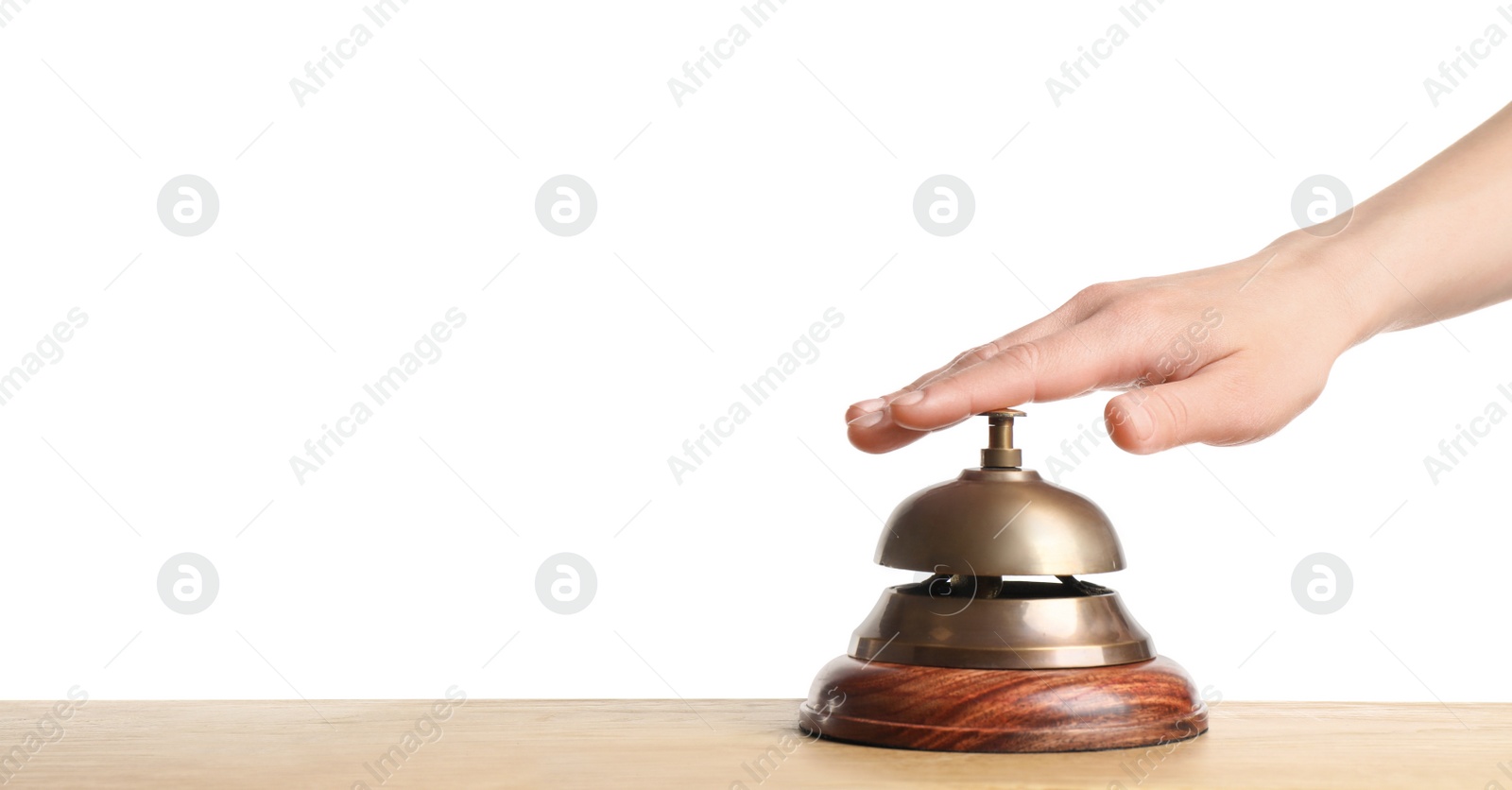 Photo of Woman ringing hotel service bell at wooden table