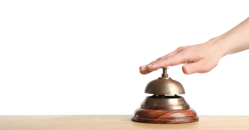 Woman ringing hotel service bell at wooden table