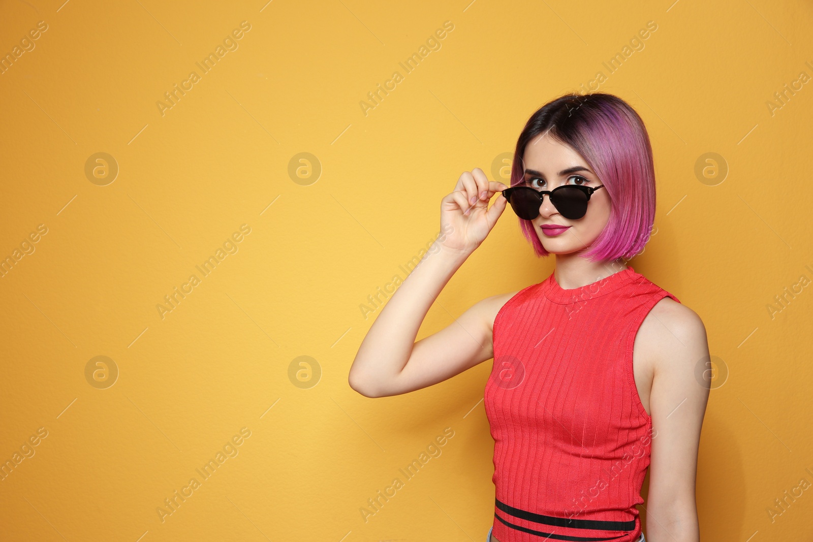 Photo of Young woman with trendy hairstyle wearing sunglasses against color background