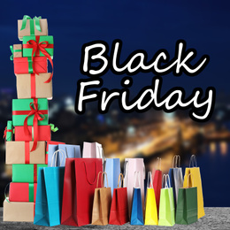 Image of Black Friday. Many shopping bags with gift boxes and blurred cityscape on background