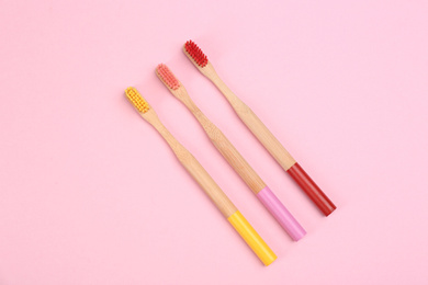 Photo of Toothbrushes made of bamboo on pink background, flat lay
