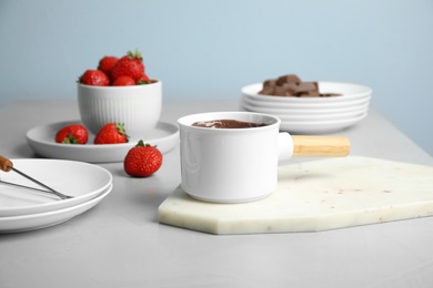 Photo of Fondue pot with chocolate and strawberry on grey table