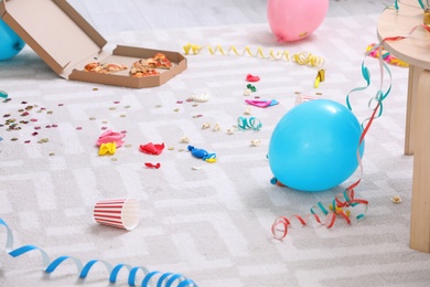 Photo of Messy floor with popped balloons and streamers after party, indoors