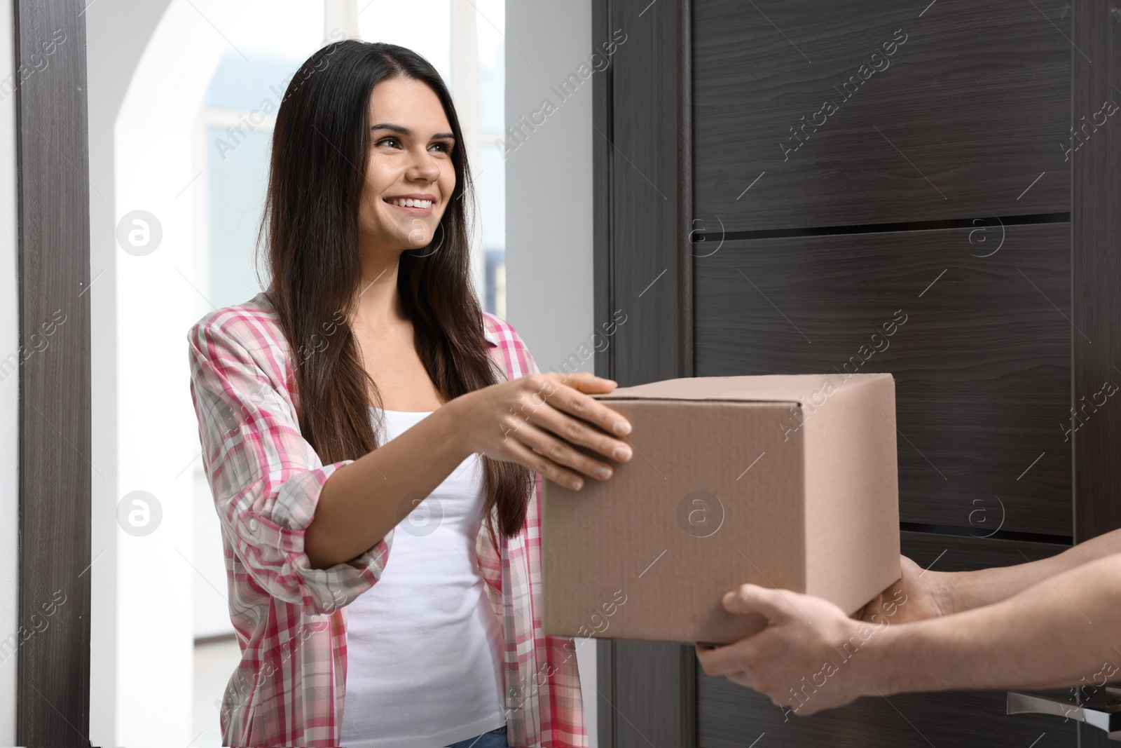 Photo of Woman receiving parcel from courier at home, closeup