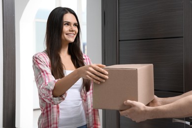 Photo of Woman receiving parcel from courier at home, closeup