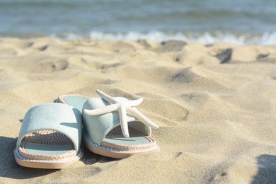 Photo of Stylish slippers and dry starfish on sandy beach near sea, space for text
