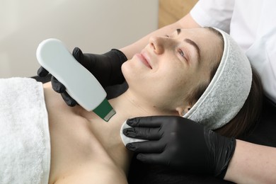 Photo of Cosmetologist using ultrasonic scrubber, closeup. Client having cleansing procedure in clinic