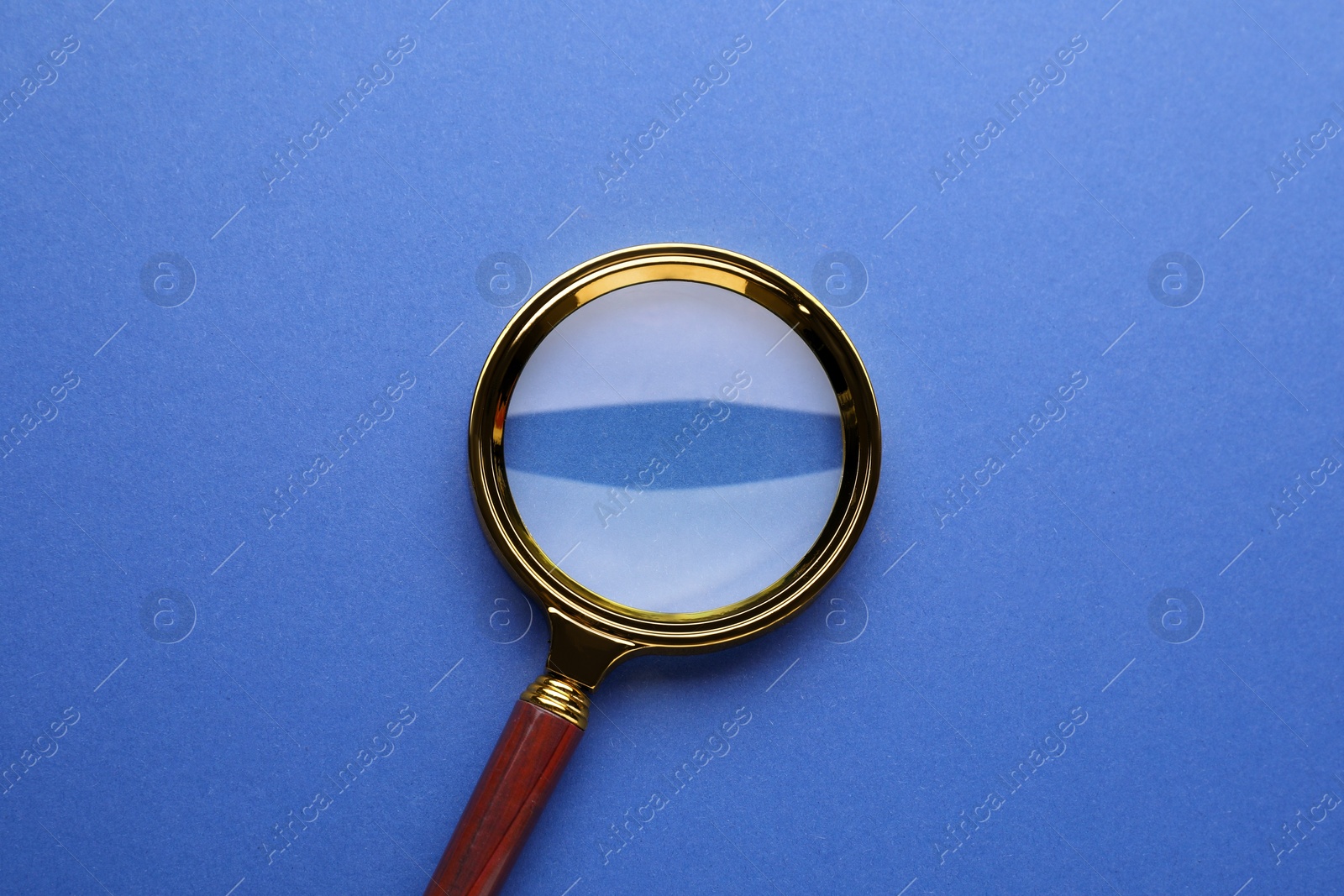 Photo of Magnifying glass on blue background, top view