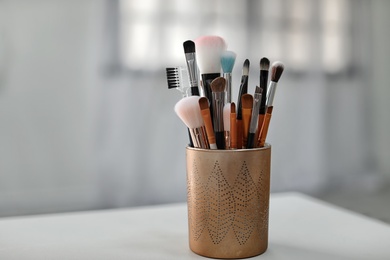 Holder with makeup brushes on table