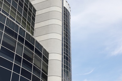 Modern building with tinted windows against sky, low angle view. Urban architecture