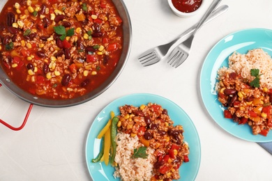 Chili con carne served with rice on light table, top view