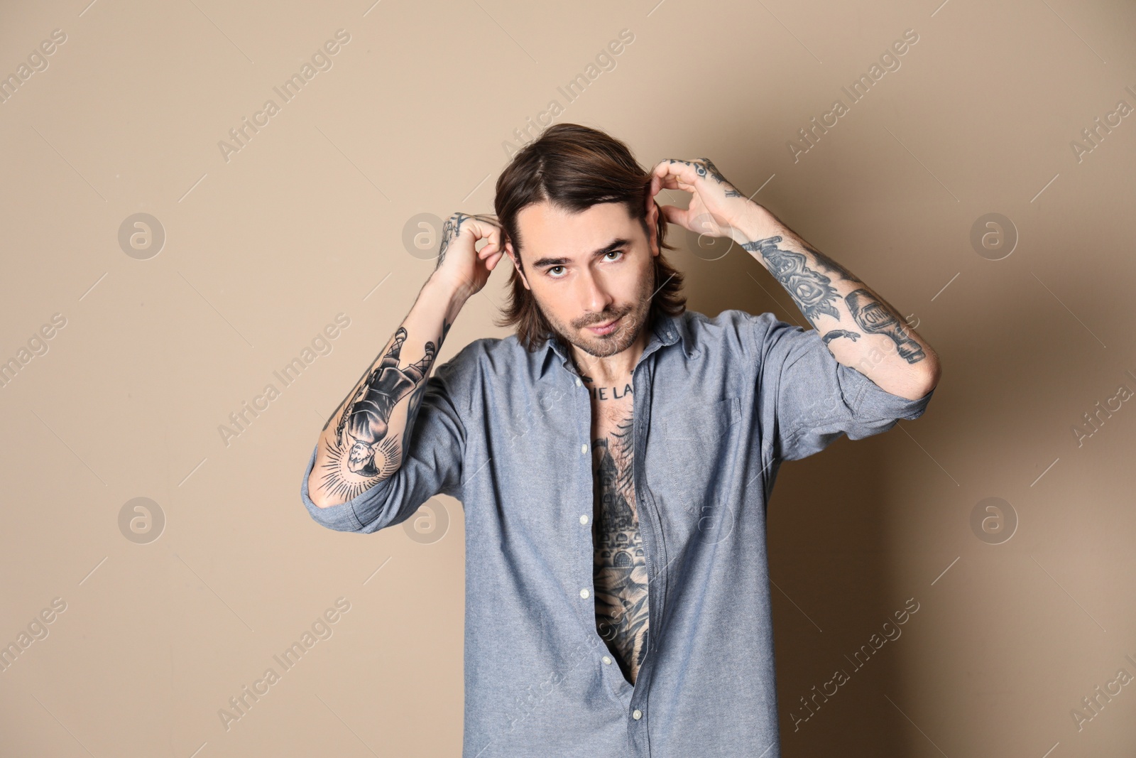 Photo of Young man with tattoos on body against beige background