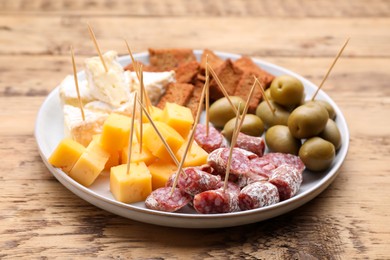 Photo of Toothpick appetizers. Pieces of cheese, sausage and olives on wooden table