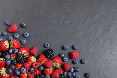 Photo of Many different fresh ripe berries on dark grey table, flat lay. Space for text