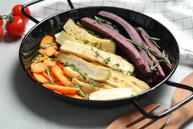 Raw cut carrots in frying pan on light grey table, closeup