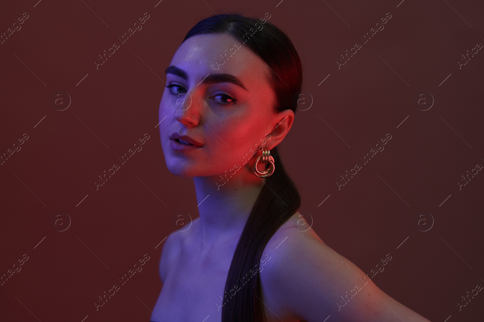 Photo of Portrait of beautiful young woman on color background in neon lights