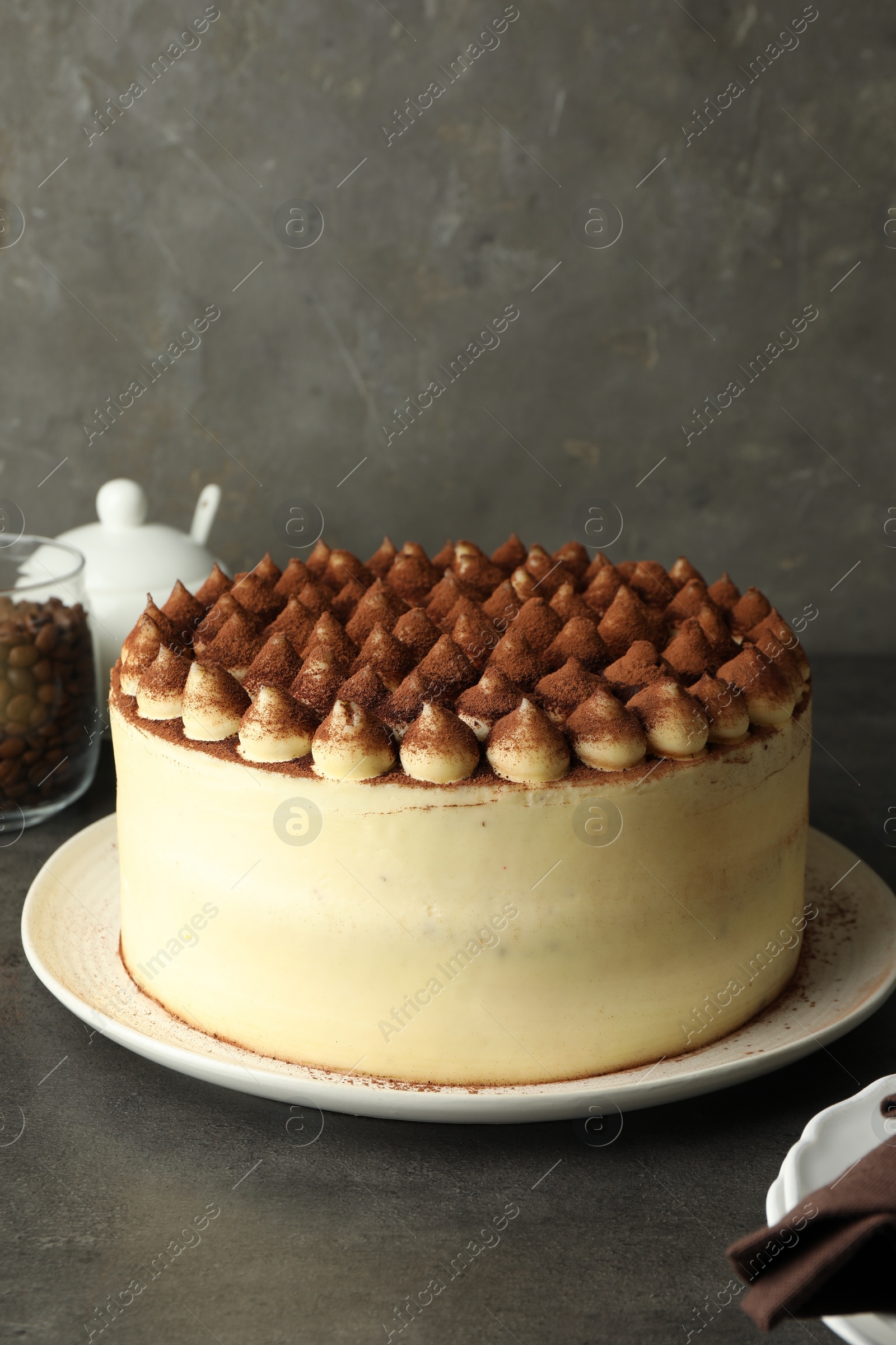 Photo of Delicious tiramisu cake with cocoa powder on grey table, space for text