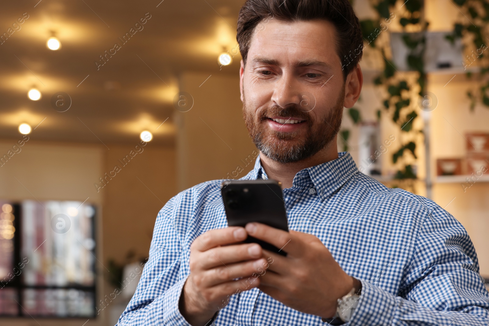 Photo of Handsome man using modern smartphone in cafe