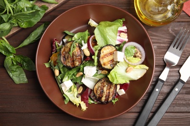 Photo of Delicious salad with roasted eggplant, feta cheese and arugula served on wooden table, flat lay