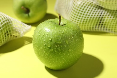 Photo of Ripe apple with water drops on light green background, closeup