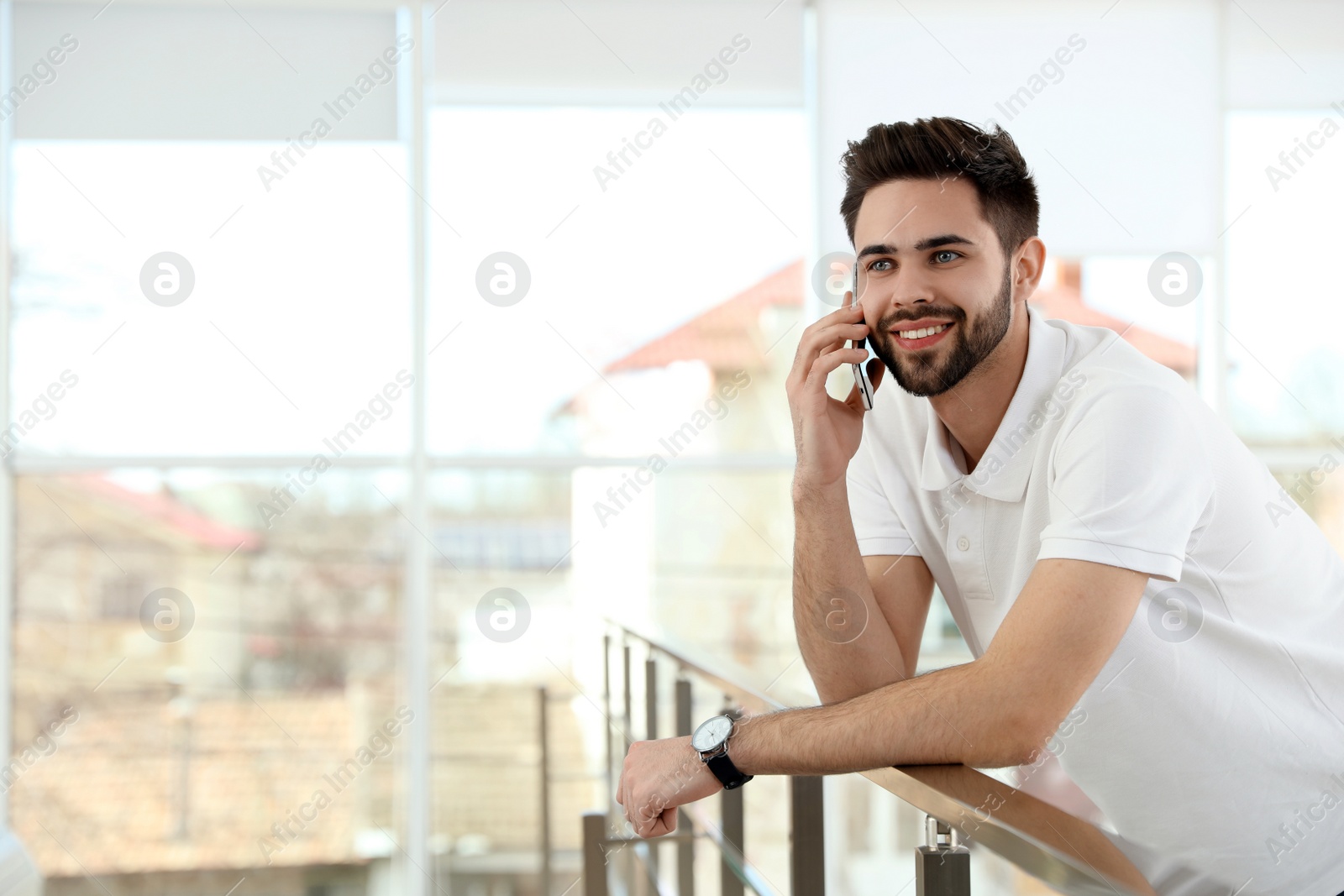 Photo of Portrait of handsome man talking on phone in light room