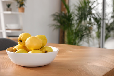 Ripe quinces on wooden table at home