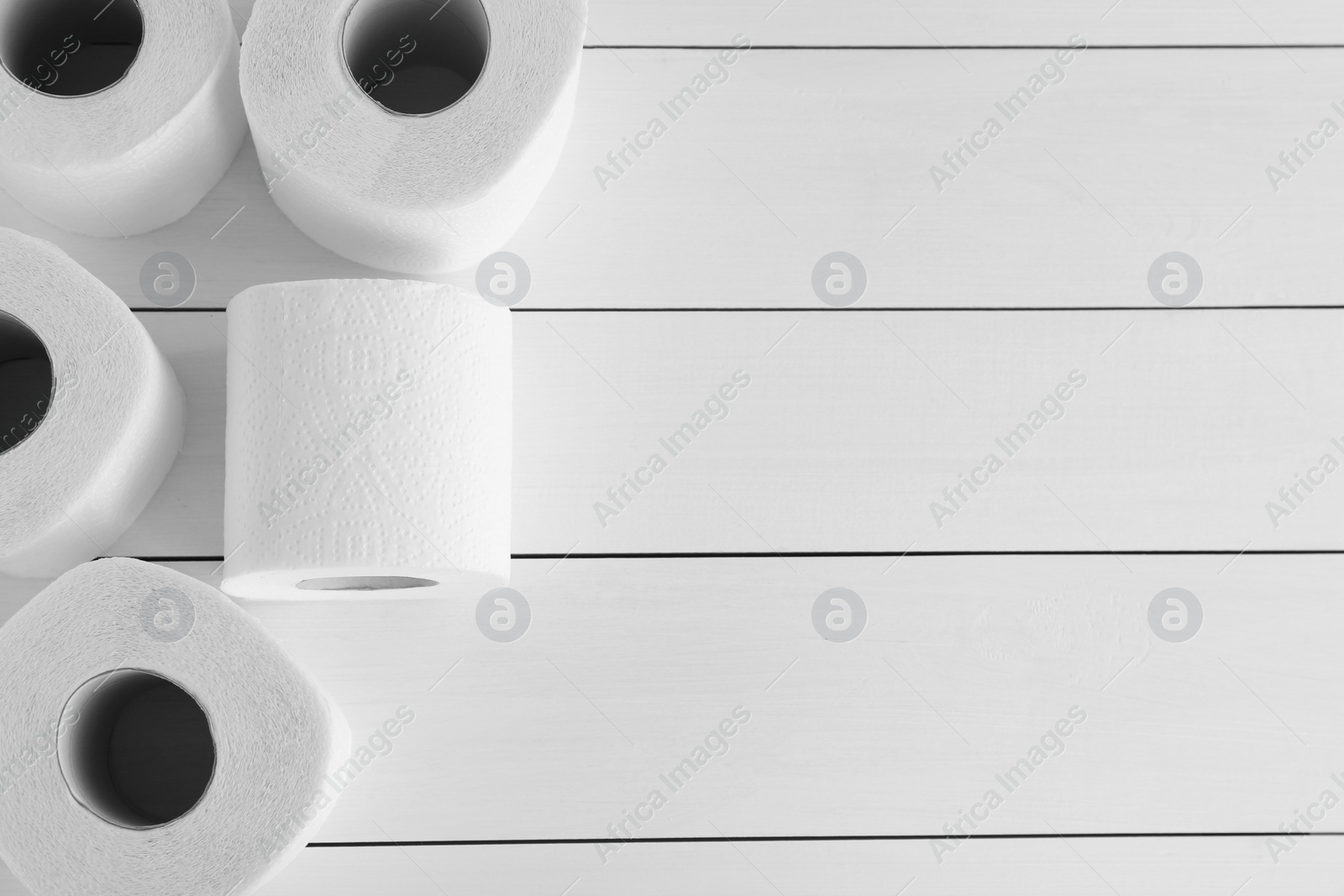 Photo of Many soft toilet paper rolls on white wooden table, flat lay. Space for text