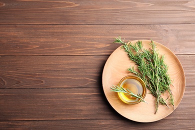 Flat lay composition with fresh rosemary oil on wooden background