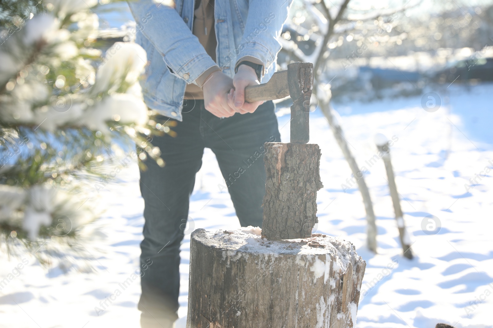 Photo of Man chopping wood with axe outdoors on winter day, closeup