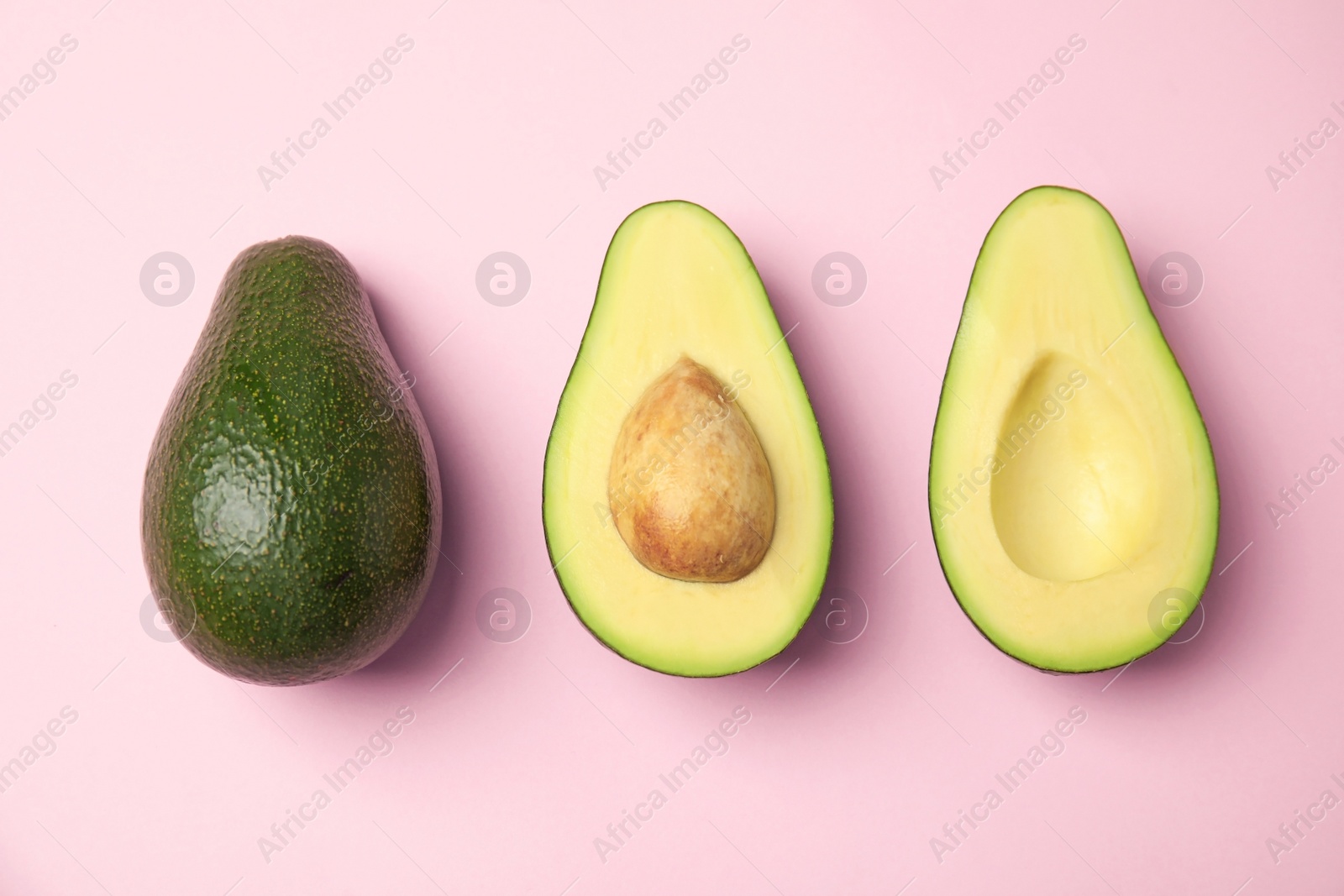 Photo of Cut and whole fresh ripe avocados on pink background, flat lay