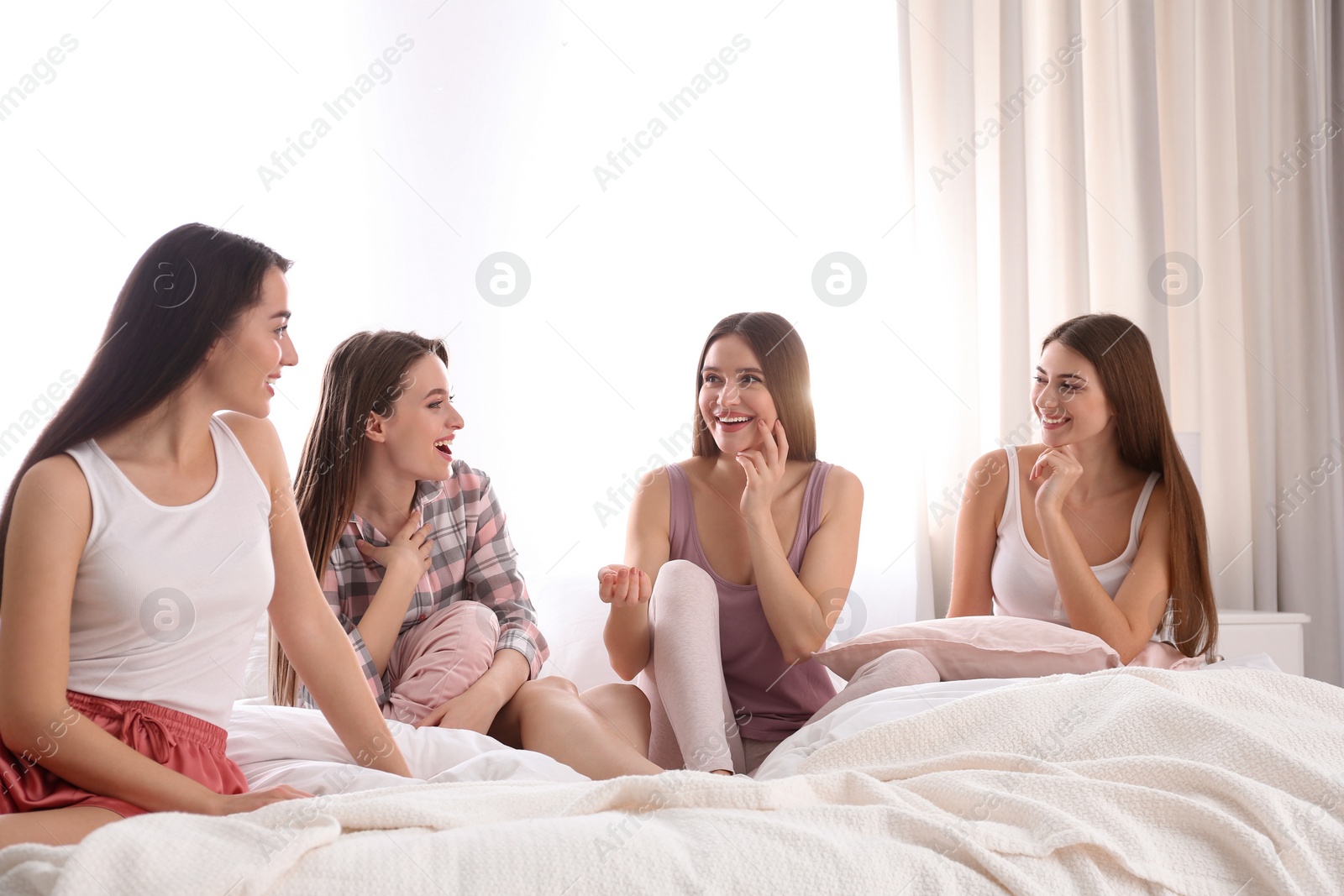 Photo of Beautiful young ladies on bed at pamper party. Woman's Day