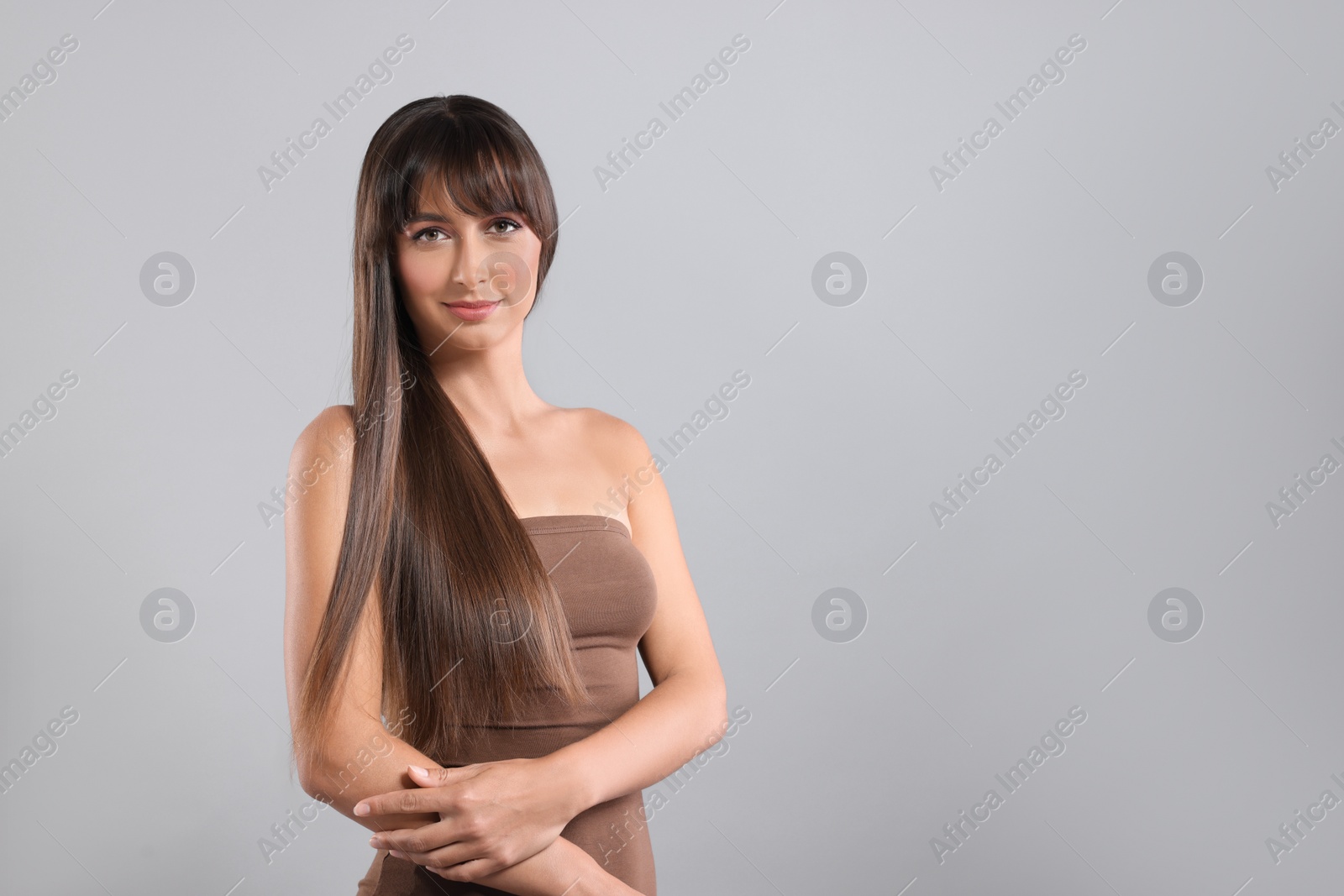 Photo of Hair styling. Portrait of beautiful woman with straight long hair on grey background, space for text